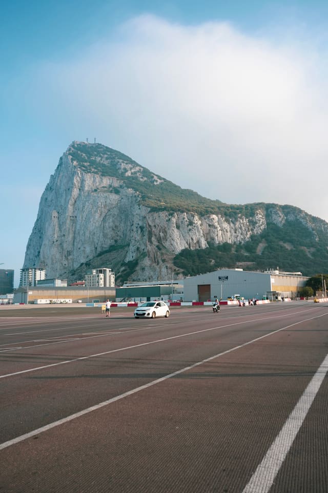 The sheer north face of the Rock, seen from the middle of the airport runway that the road into town crosses.